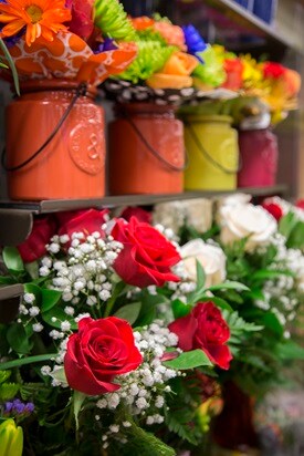 Flower arrangements in colorful jars on shelf 