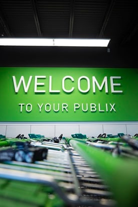 Publix shopping carts in bottom foreground with new decor Welcome to Publix sign centered above