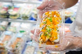 Hands holding package with fresh sushi roll